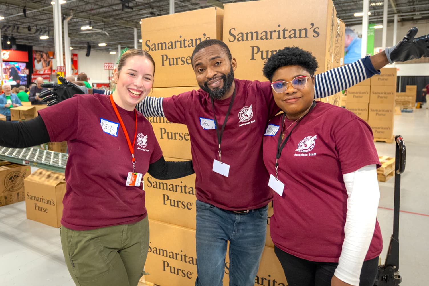 Group of seasonal employees smiling and standing together infront of a pallet full of Samaritan's Purse boxes