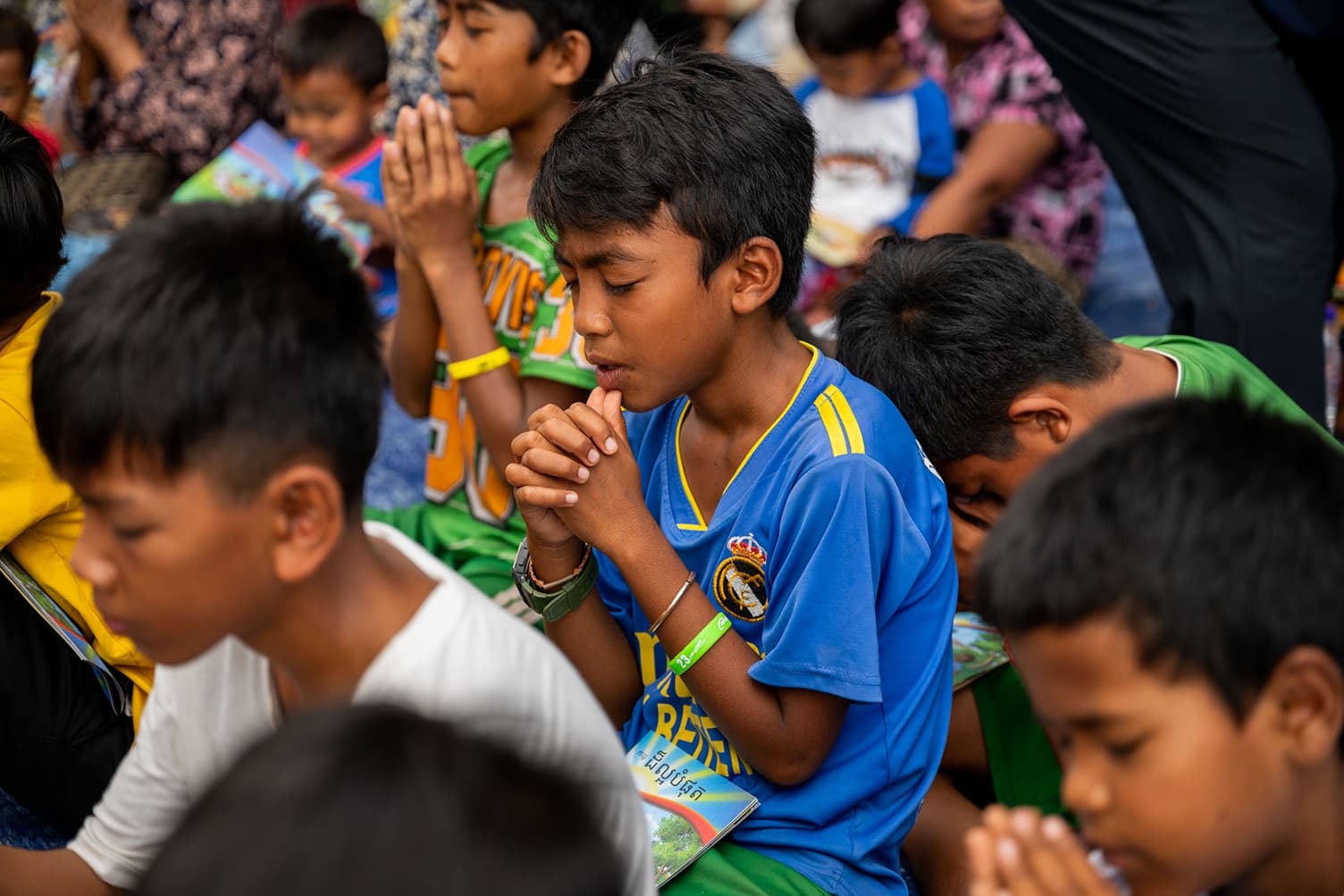 Young boy at Operation Christmas Child Event in Cambodia praying