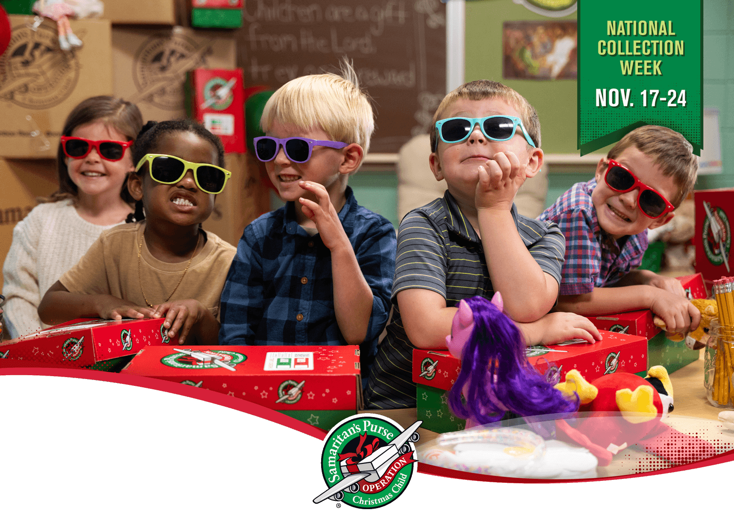 Group of young kids making silly expressions while wearing bright colored sunglasses and standing behind Operation Christmas Child shoeboxees and toys. COPY: National Collection Week - November 17 through 24