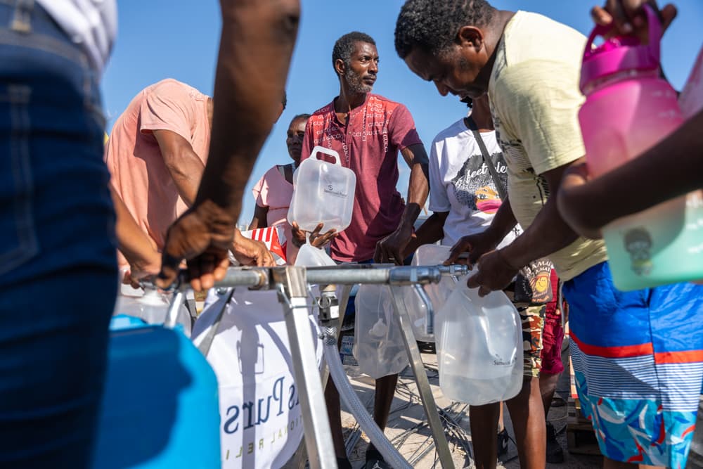 People filling containers with clean water from a Samaritan’s Purse community filtration system in Jamaica after Hurricane Melissa.