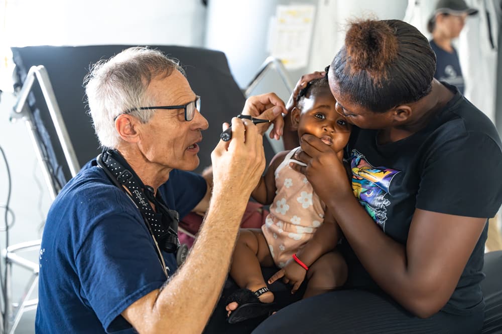 A Samaritan’s Purse physician examines a young patient as her mother offers comfort inside our Emergency Field Hospital in Black River, Jamaica.
