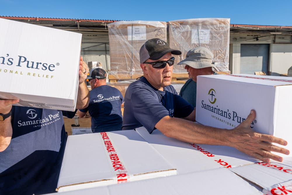 Samaritan’s Purse workers load white relief boxes marked “International Relief” onto pallets for shipment to Jamaica.