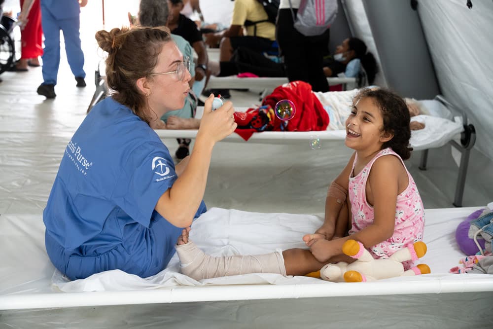 A young patient enjoys blowing bubbles with one of our staff as her injured leg begins to recover.