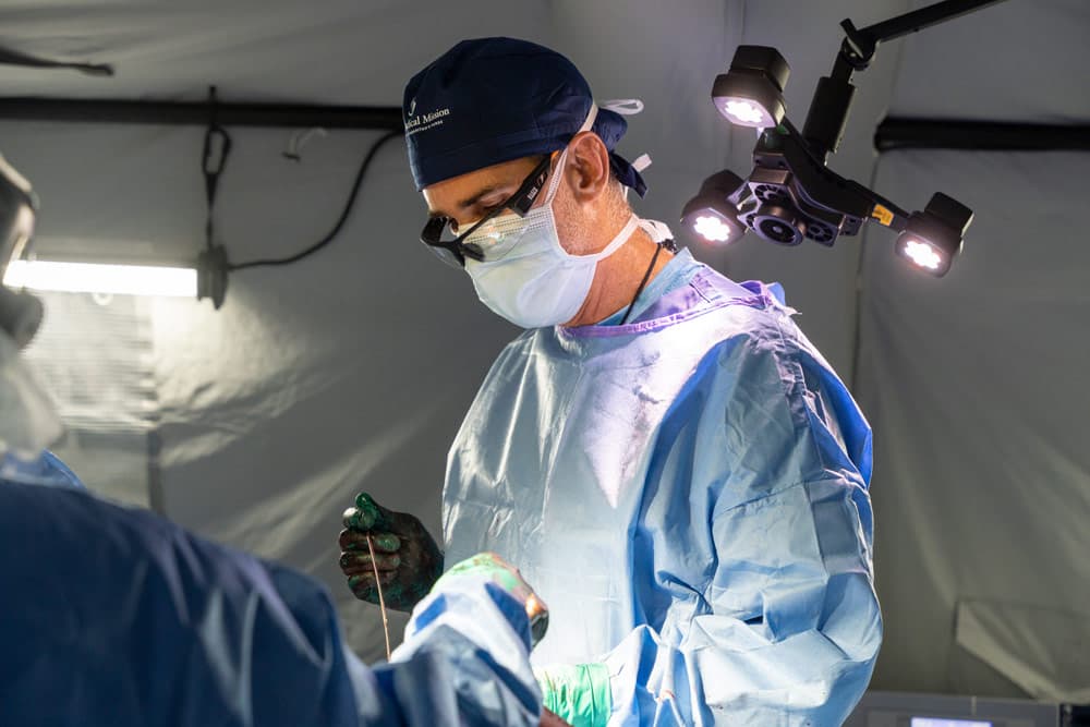 The surgical team performs an orthopedic repair on a patient's injured leg at the Emergency Field Hospital.