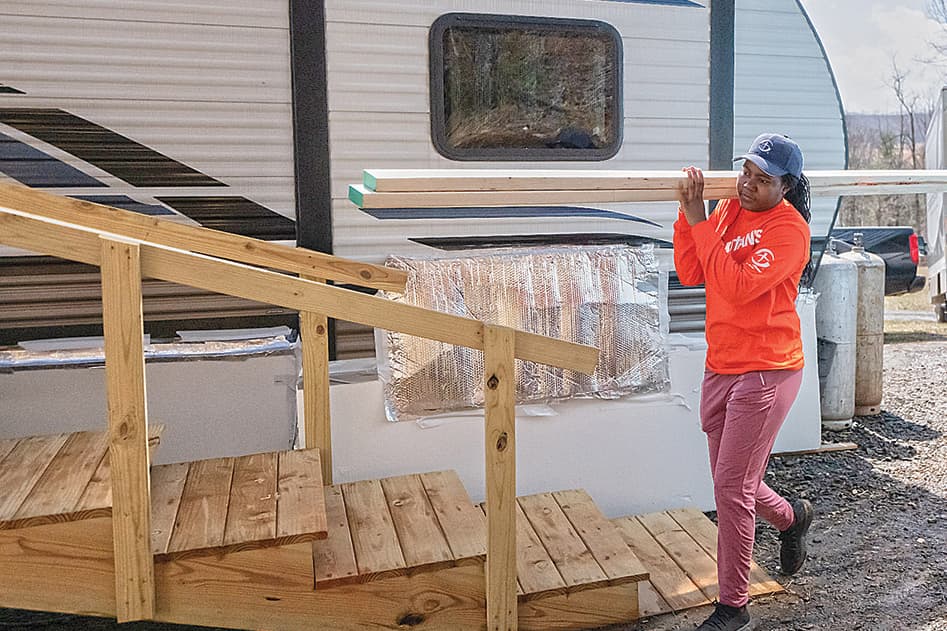 Woman carrying lumber at a rebuild site.