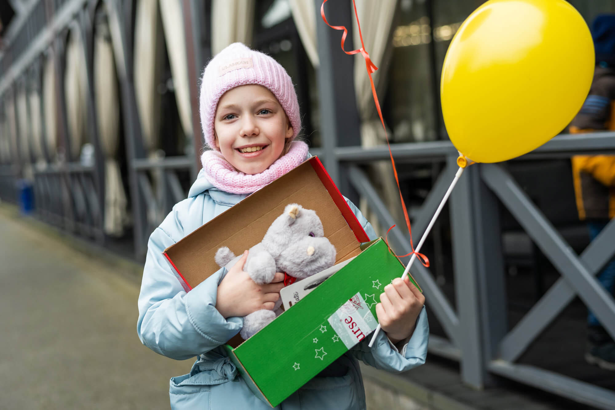 a Ukrainian girl stands smiling with her Operation Christmas Child shoebox filled with toys