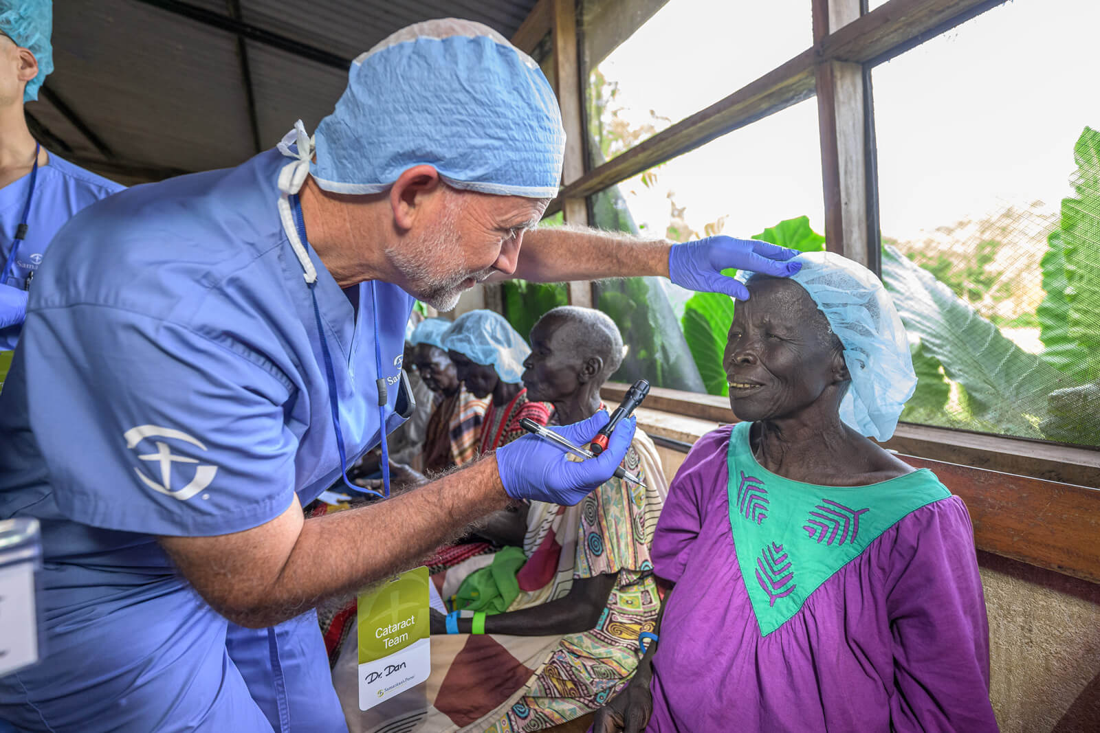 A member of the Samaritan Purse cataract team inspects a woman's eyes after cataract surgery