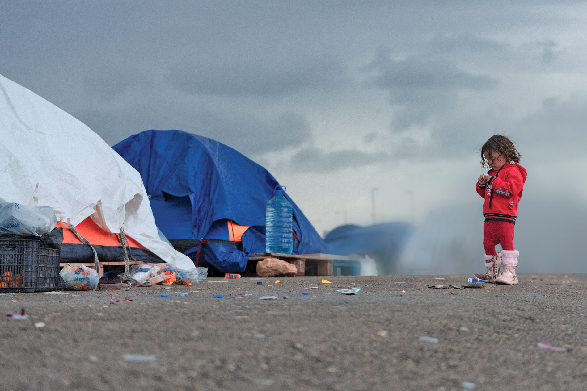 A child in lebanon stands in front of tents.