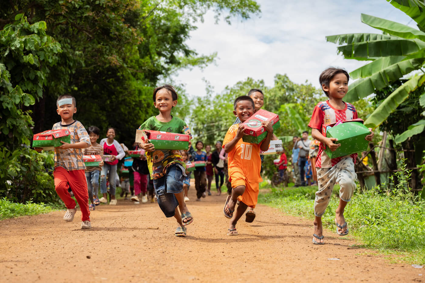 smiling children running with their shoebox gifts in Cambodia