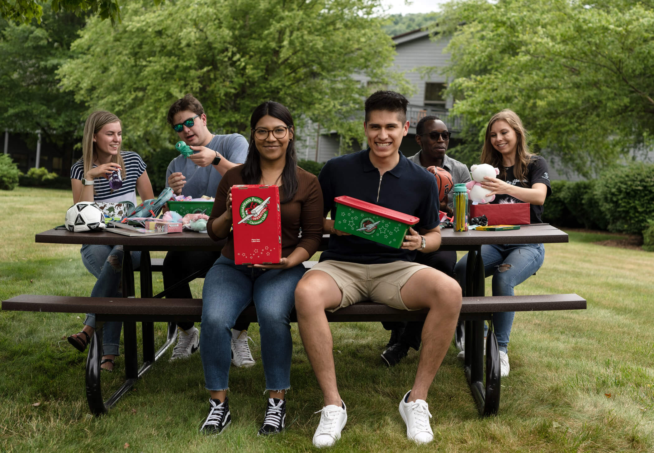 Students sitting on a bench packing Operation Christmas Child shoeboxes.