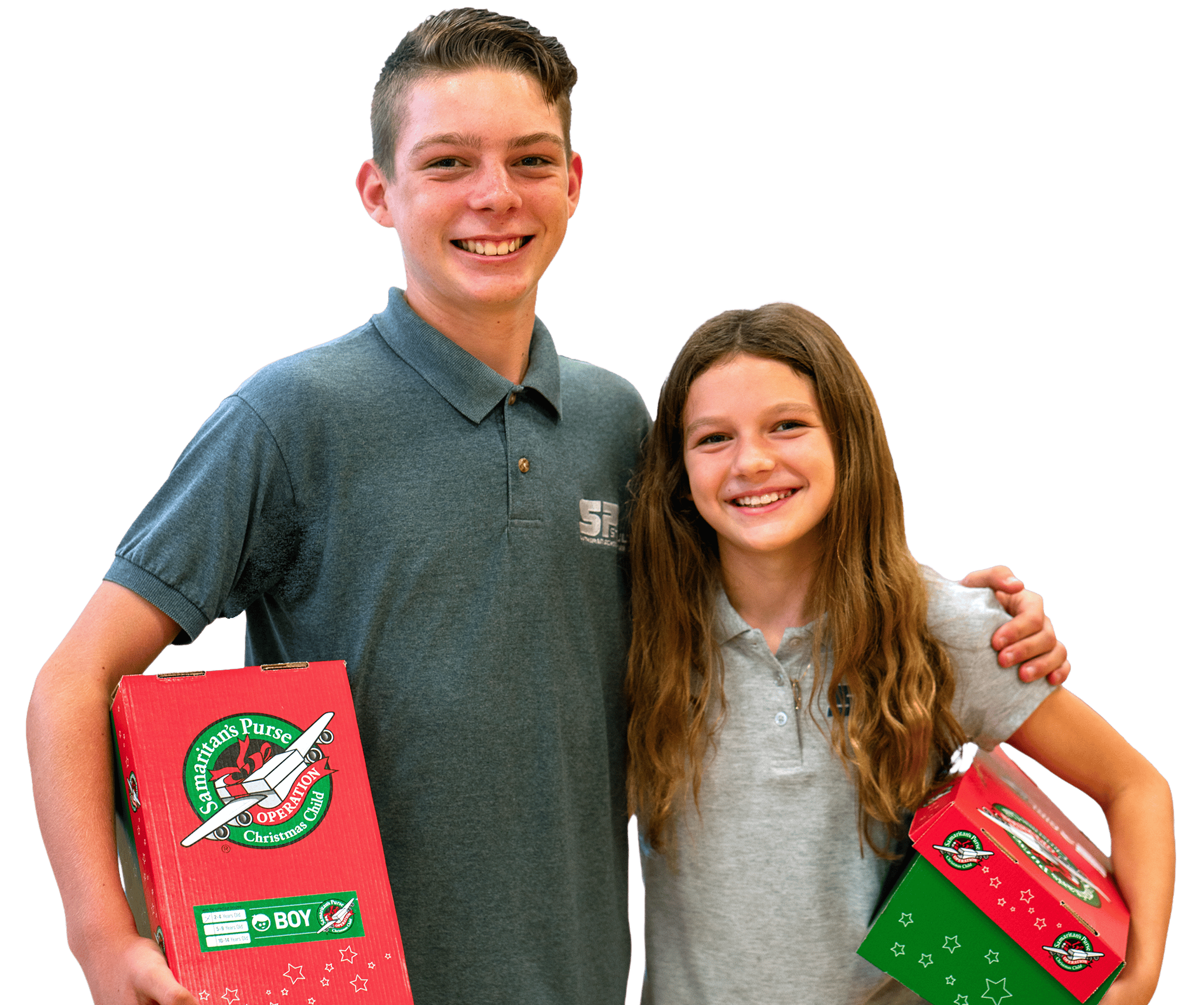 A young boy and girl standing together smiling with an Operation Christmas Child shoebox in their arms