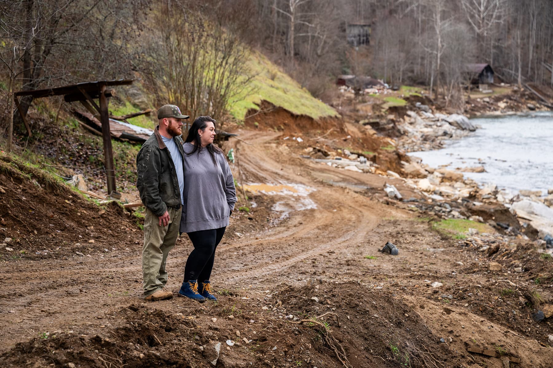Vanessa and Casey standing together a river on dirt road looking out at the water