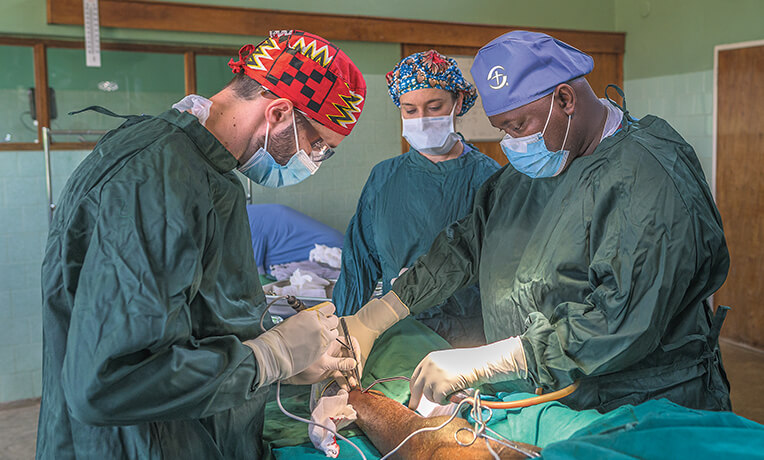 Three surgeons doing surgery on patient.