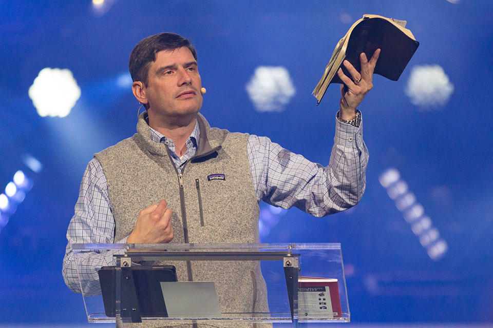 Will Graham at podium holding up The Bible.